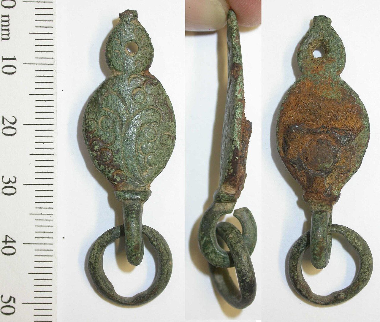 Post-medieval copper-alloy sword-belt fitting, with suspension loop in which a small copper alloy ring survives. The mount has an oval central lobe, with engraved foliate decoration, with numerous pun