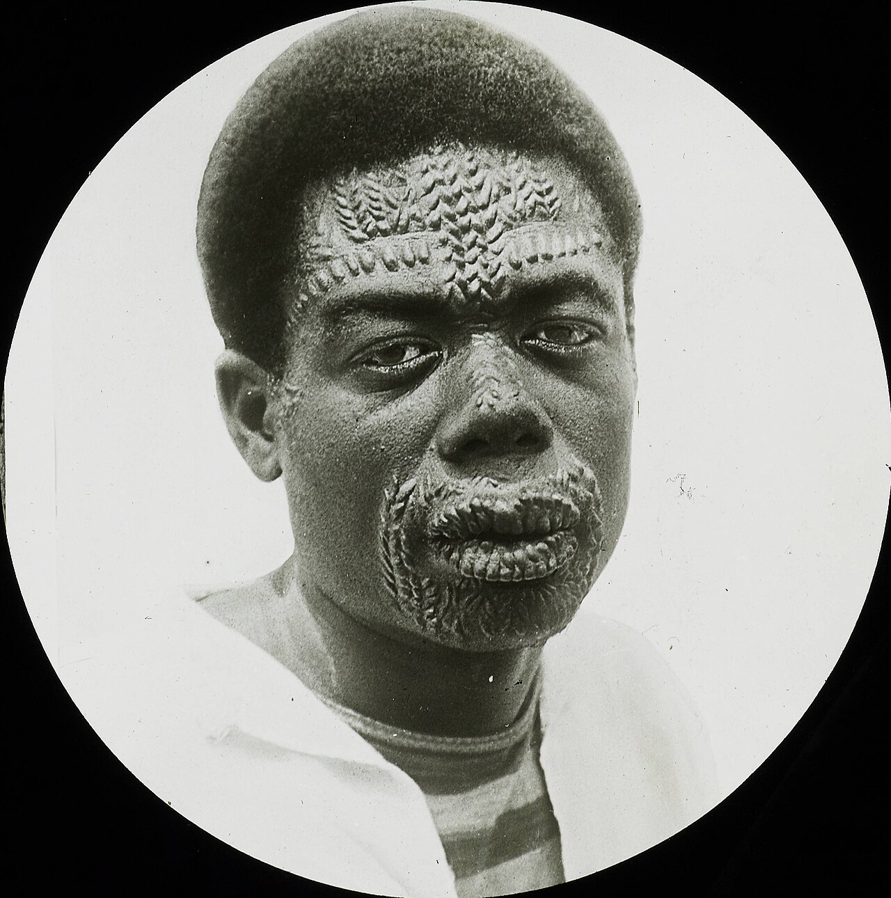 Scarification designs, Congo, ca. 1900-1915Black and white lantern slide showing a Congolese man with designs made on his face through the process of scarification, colonial Belgian Congo (present da