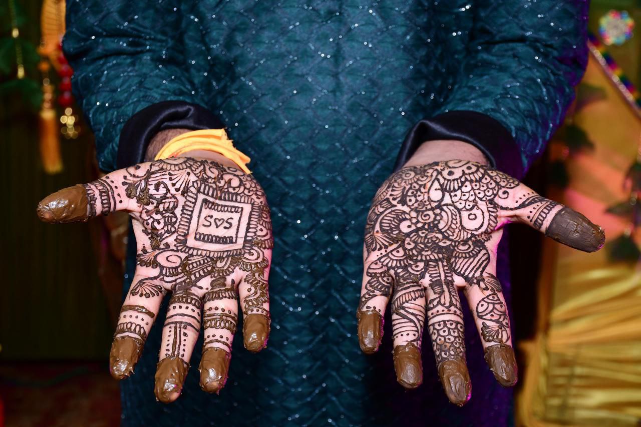 The groom's mehndi ceremony is a meaningful and beautiful celebration that signifies the start of his wedding festivities. As he sits, his hands embellished with detailed, rich henna designs, a feelin
