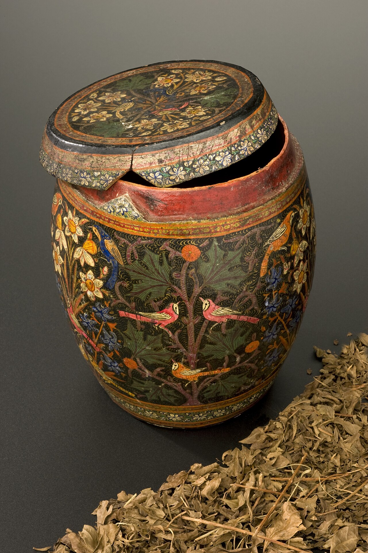 Box, lacquer in shape of a barrel, detachable lid beautifully painted externally with bird and floral design, one third full of dried henna leaves, from Turkish pharmacy, Persian, 1870-1920. Contents