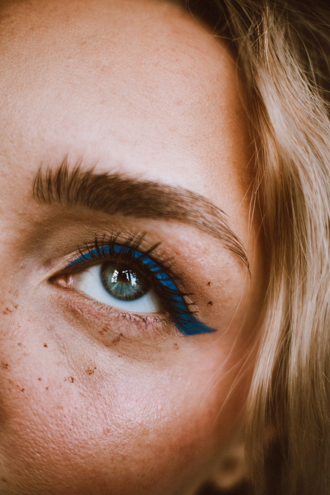 a close up of a woman's face with blue eyeliner