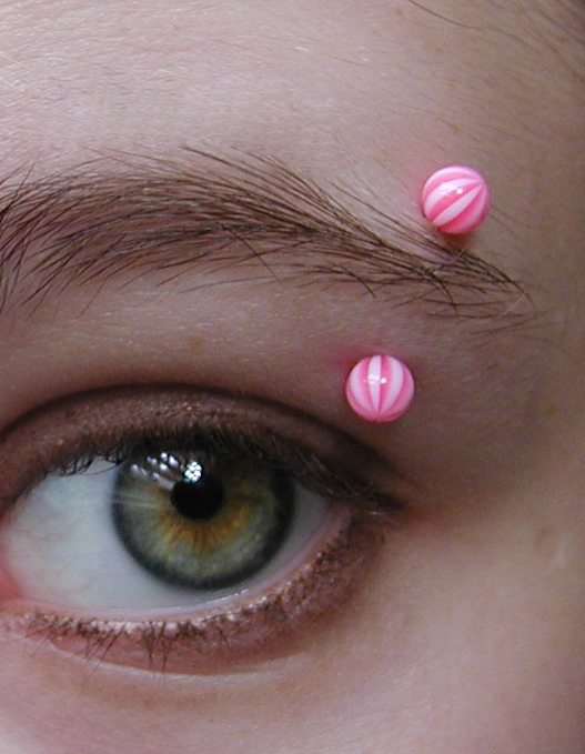 Picture of a left eyebrow piercing with a curved barbell. Subject is China Beritiech.Uploaded for the eyebrow piercing article.