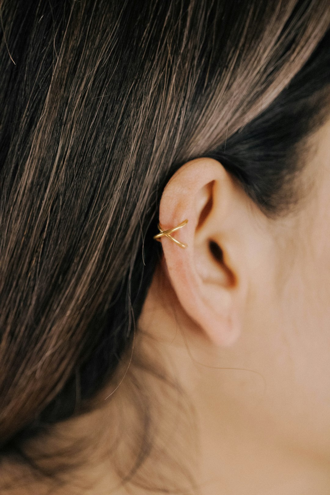 a close up of a person's ear wearing a gold earring