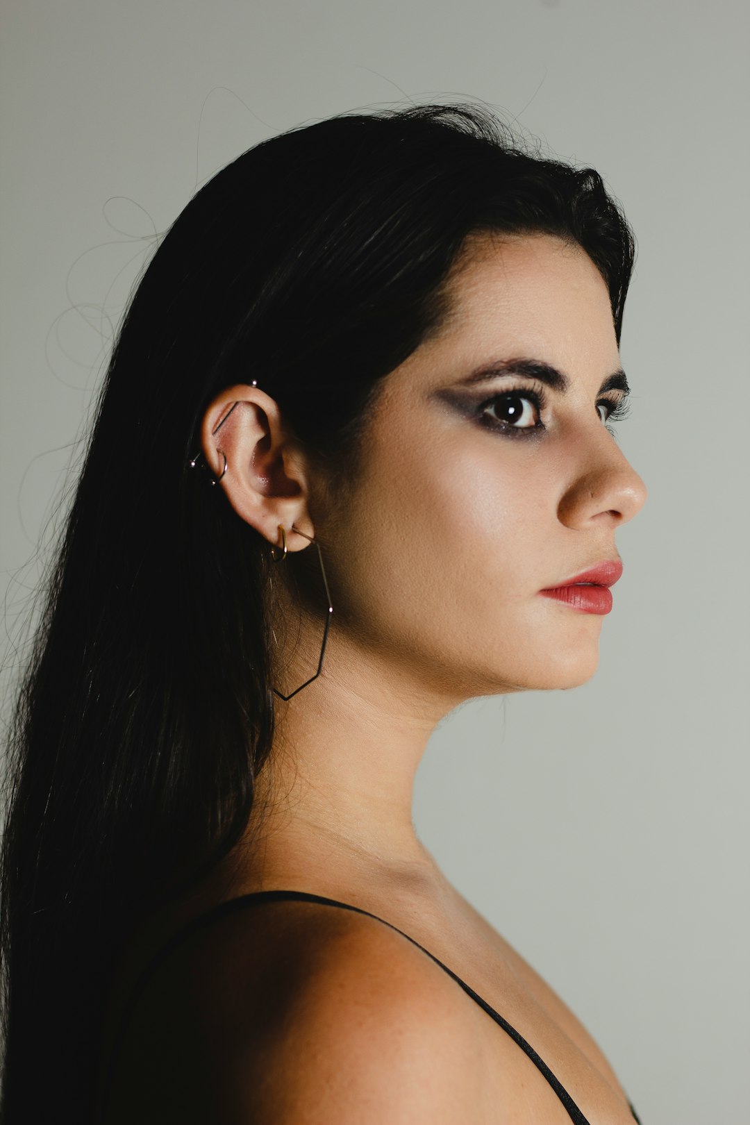 a woman with long black hair wearing a pair of earrings