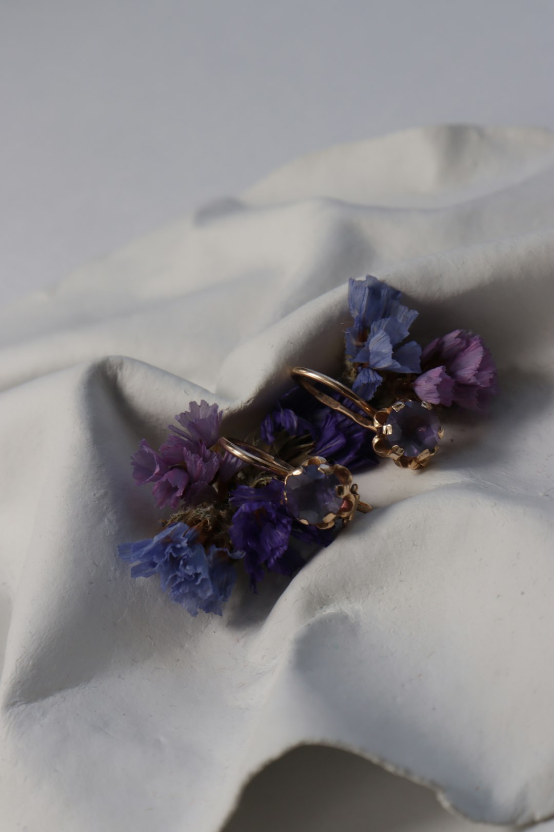 Earrings and flowers on a white cloth.