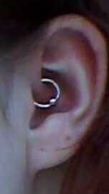 A Daith piercing, specifically a captive bead ring. The ring passes through the crus of the helix, a fold of cartilage in the ear.