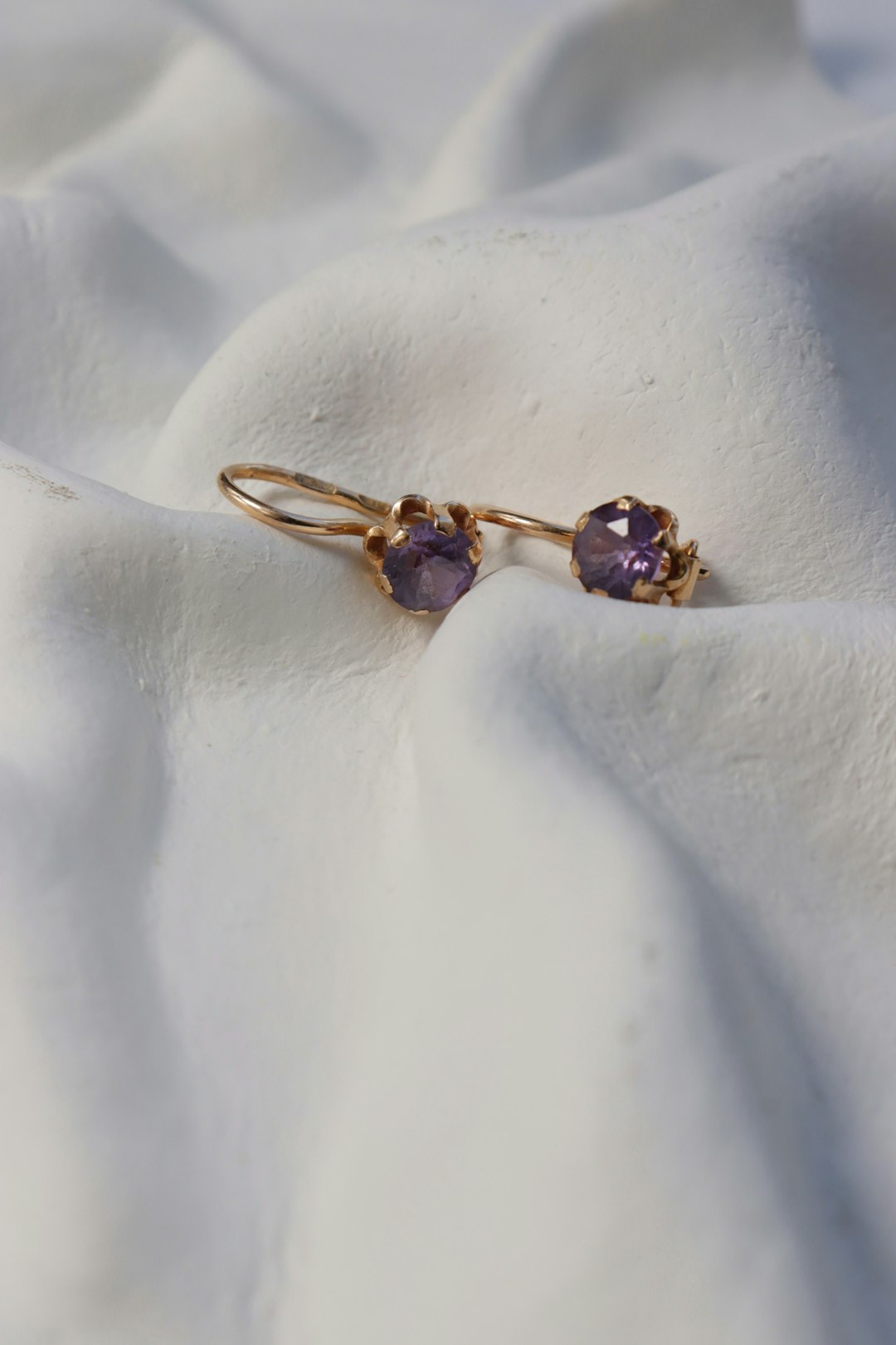 Amethyst earrings rest on a white, textured surface.