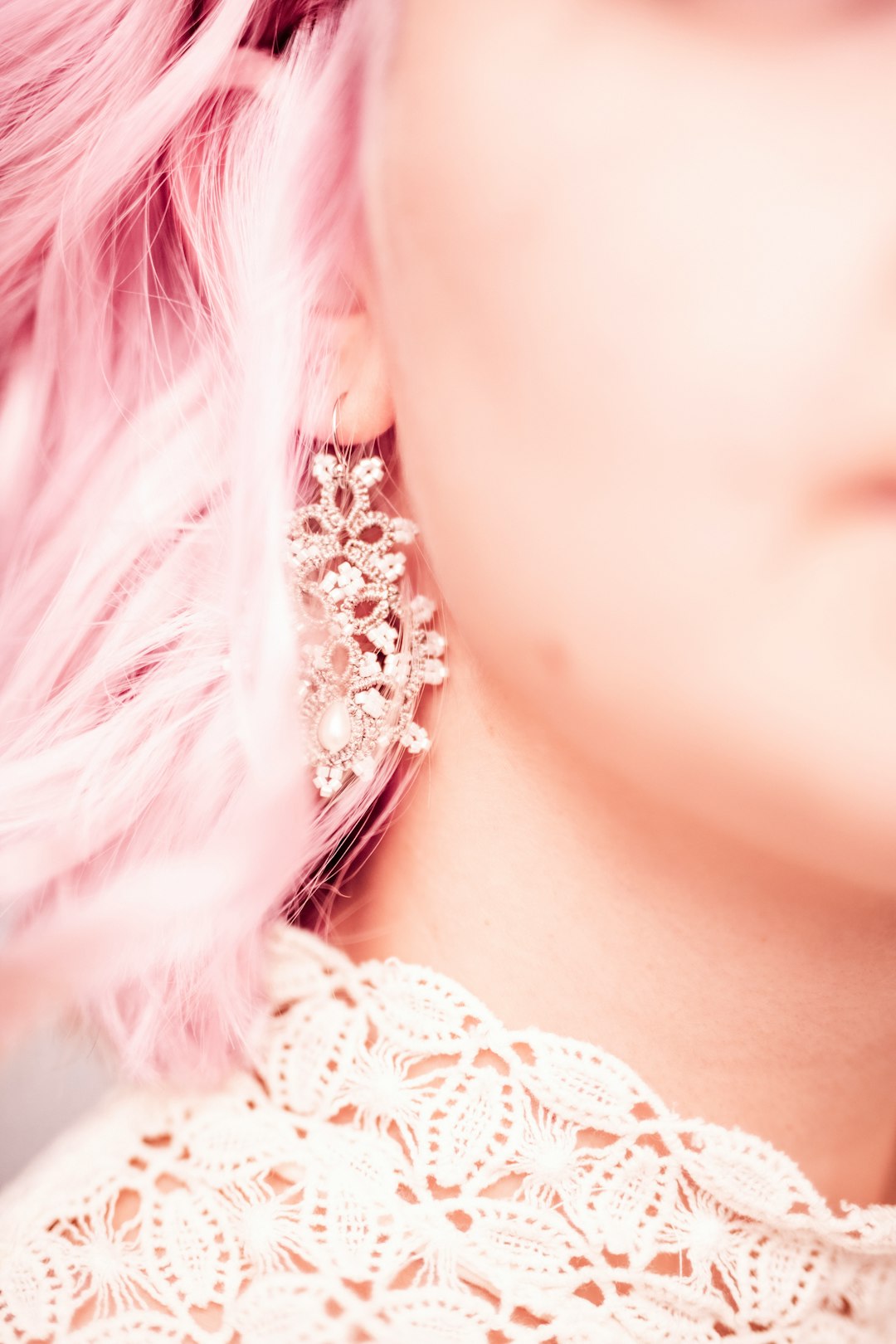 Woman with pink hair wearing ornate sparkling earrings.