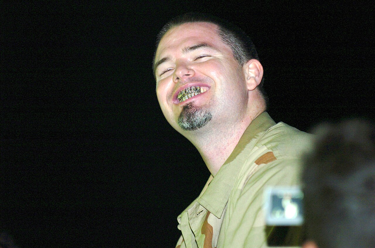 A fan snaps a picture as Paul Wall displays his signature platinum and diamond grill while singing the appropriately titled "Grillz" during the Jamie Kennedy Hip-Hop Comedy Tour at Camp Liberty, Iraq,